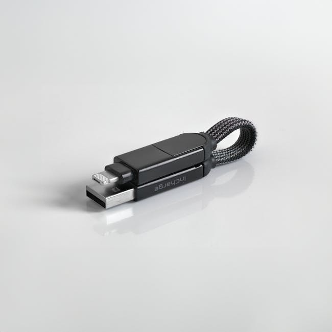 Minimalist photo of a sleek black USB flash drive with a braided loop against a white background.